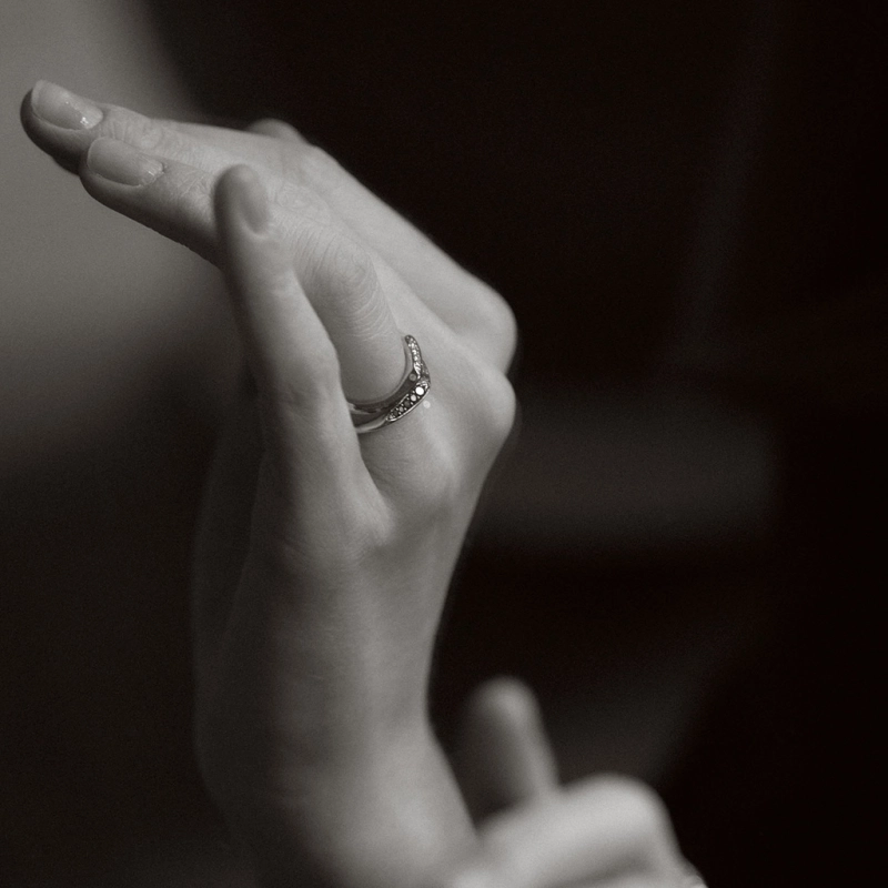 obrączka z białego i żółtego złota o nieregularnym, falistym kształcie z brylantami białymi i czarnymi projektu Marty Szafraniec, projektantki z Katowic