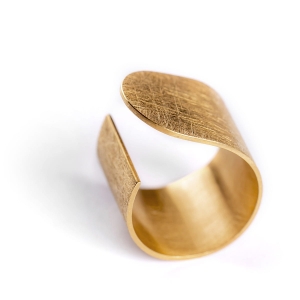 Duży pierścionek z kolekcji Halfring z mocno wyszczotkowaną matową powierzchnią, i błyszczącymi krawędziami i bokami dla kontrastu. Złocony, asymetryczny, minimalistyczny. Zaprojektowany przez Martę Szafraniec, projektantkę z Katowic.