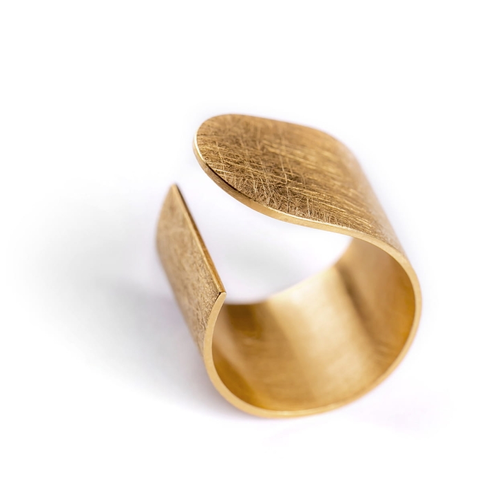 Duży pierścionek z kolekcji Halfring z mocno wyszczotkowaną matową powierzchnią, i błyszczącymi krawędziami i bokami dla kontrastu. Złocony, asymetryczny, minimalistyczny. Zaprojektowany przez Martę Szafraniec, projektantkę z Katowic.