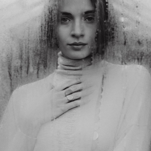 Zmysłowa kobieta en face, w jasnym golfie, w srebrnej biżuterii z tej samej kolekcji Halfring, w kolczykach, naszyjniku z połówek i w dwóch pierścionkach, symetrycznym i asymetrycznym. Satynowe i wybłyszczone, dobrym stylu marki Saffa.